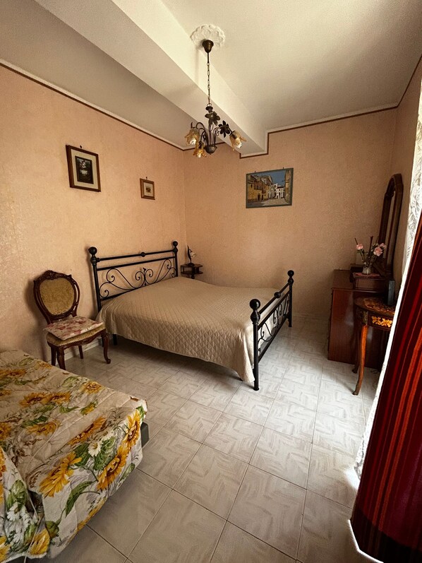 Ein Schlafzimmer mit einem Bett, einem Sessel, einem Schminktisch und einem Deckenventilator.