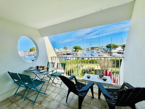 Een balkon met een tafel en stoelen, met uitzicht op een jachthaven met boten.