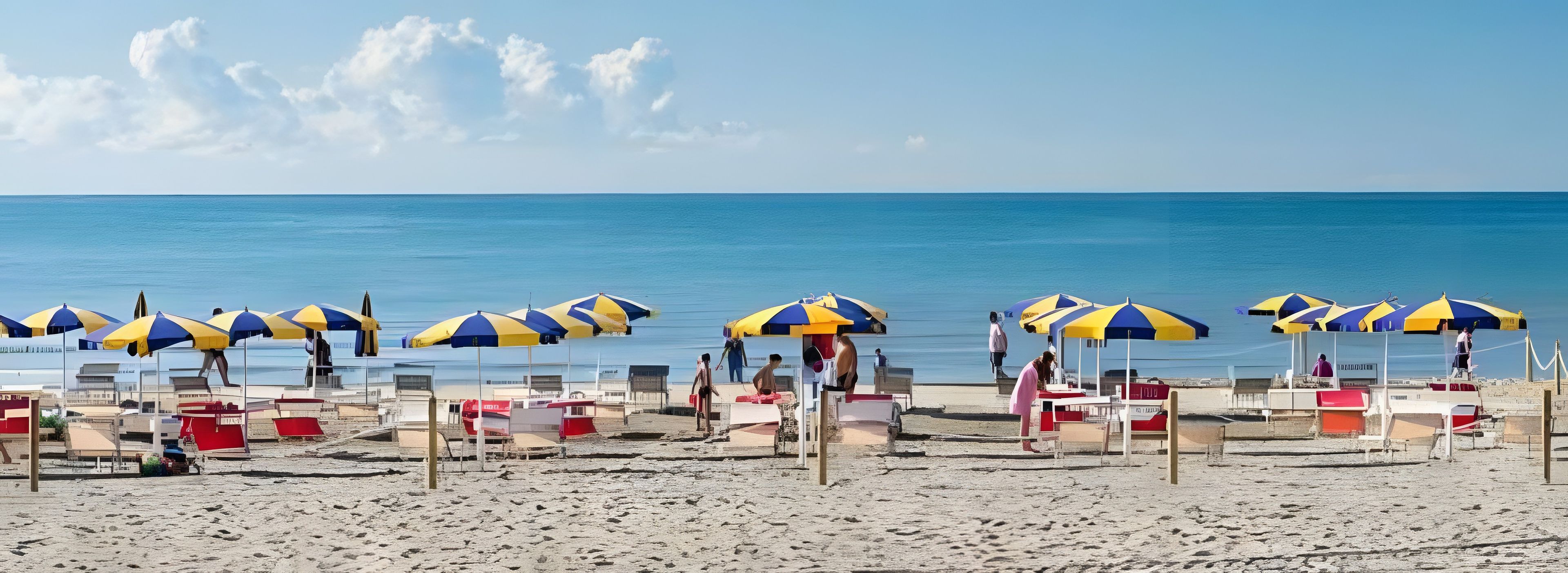 A beach with rows of beach chairs and umbrellas, a clear sky, and the ocean in the background.