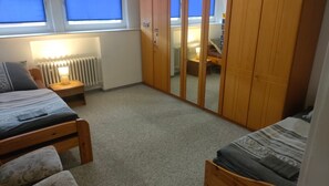 A bedroom with two beds, a wardrobe, a radiator, and a window with blinds. - Apartment 'Marienmünster' with Wi-Fi (Marienmünster)