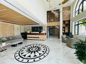 A modern lobby with a reception desk, seating area, and a large decorative floor pattern. - HOTEL SALA LAN ANH (Phuoc An)