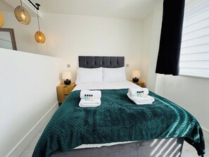 A neatly made bed with a green quilt, two white towels, and toiletries on the bed. - 
Modern Executive Studio 11 | Central Swindon (Swindon)