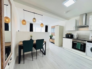 A modern kitchen with a dining area, white cabinetry, and hanging pendant lights. - 
Modern Executive Studio 11 | Central Swindon (Swindon)