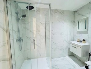 A modern bathroom with a glass-enclosed shower, a white marble tiled wall, and a white vanity with a mirror. - 
Modern Executive Studio 11 | Central Swindon (Swindon)
