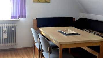 Ein Zimmer mit einem Bett, einem Tisch mit Stühlen, einem Heizkörper und einem Bild an der Wand.
