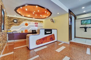 Un espace d’accueil au design moderne, comprenant un comptoir de réception, une horloge et un téléviseur fixé au mur.