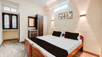 Ein Schlafzimmer mit einem Bett, einem Holzschrank und einem Badezimmer mit Spiegel und Waschbecken.