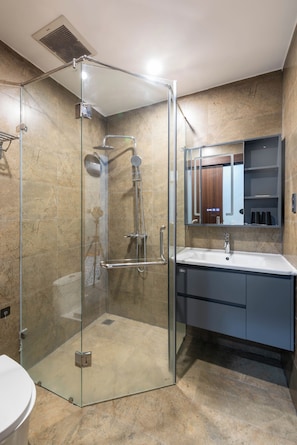 A modern bathroom with a glass-enclosed shower, a sink, and a vanity with a mirror. - LEE NÔM VILLA DANANG (Ngũ Hành Sơn)