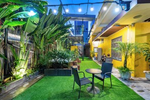 An outdoor patio with artificial grass, seating, and potted plants. - LEE NÔM VILLA DANANG (Ngũ Hành Sơn)