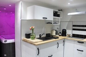 Une cuisine moderne avec des meubles blancs, un évier noir et une machine à café.