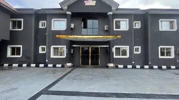 A building with a dark facade, multiple windows, and a central entrance with a golden awning.