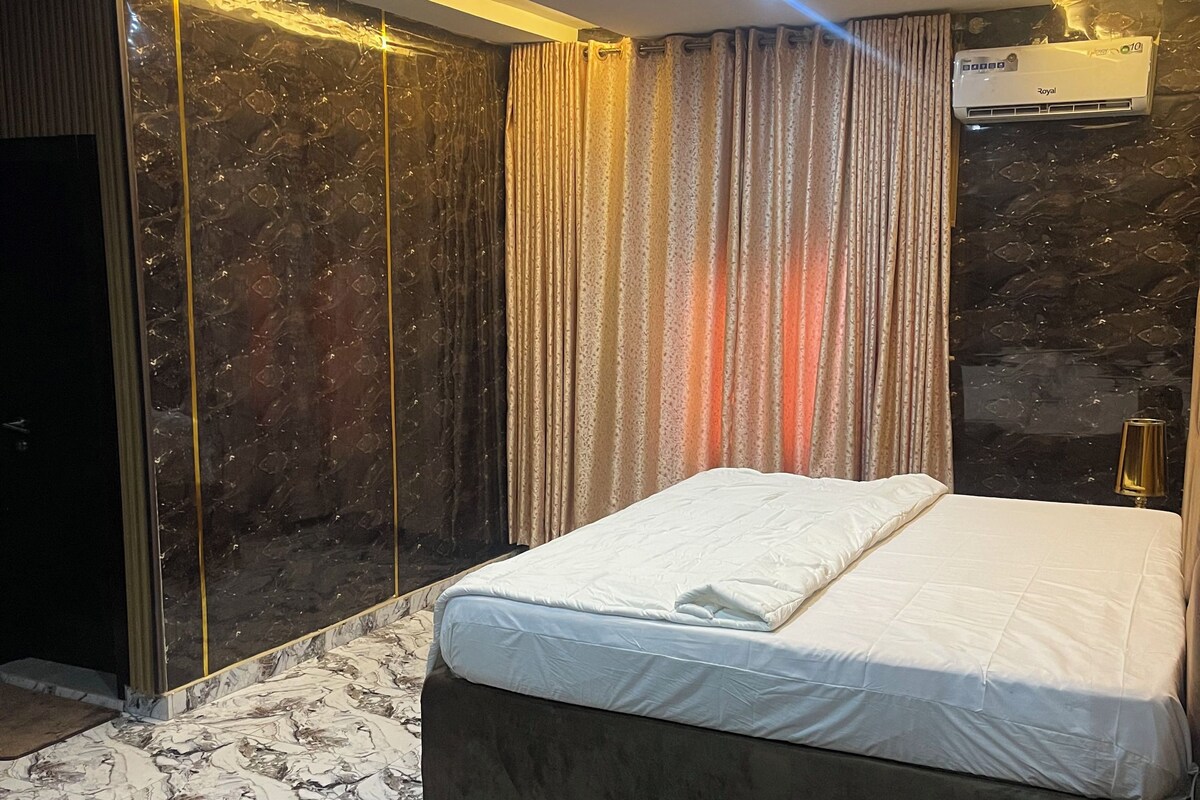 Un dormitorio moderno con una cama grande, pisos de mármol y un candelabro en el techo.