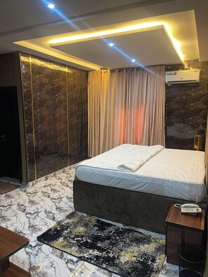Un dormitorio moderno con una cama grande, pisos de mármol y un candelabro en el techo.