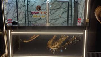 A reception desk with a marble wall background, a sign for 'DEBONY TWINZ Hotel & Suite,' and a modern light fixture.
