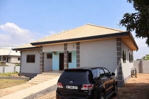 Moderni, kaksikerroksinen talo, jonka edessä autotallin edustalla on parkkeerattu auto.