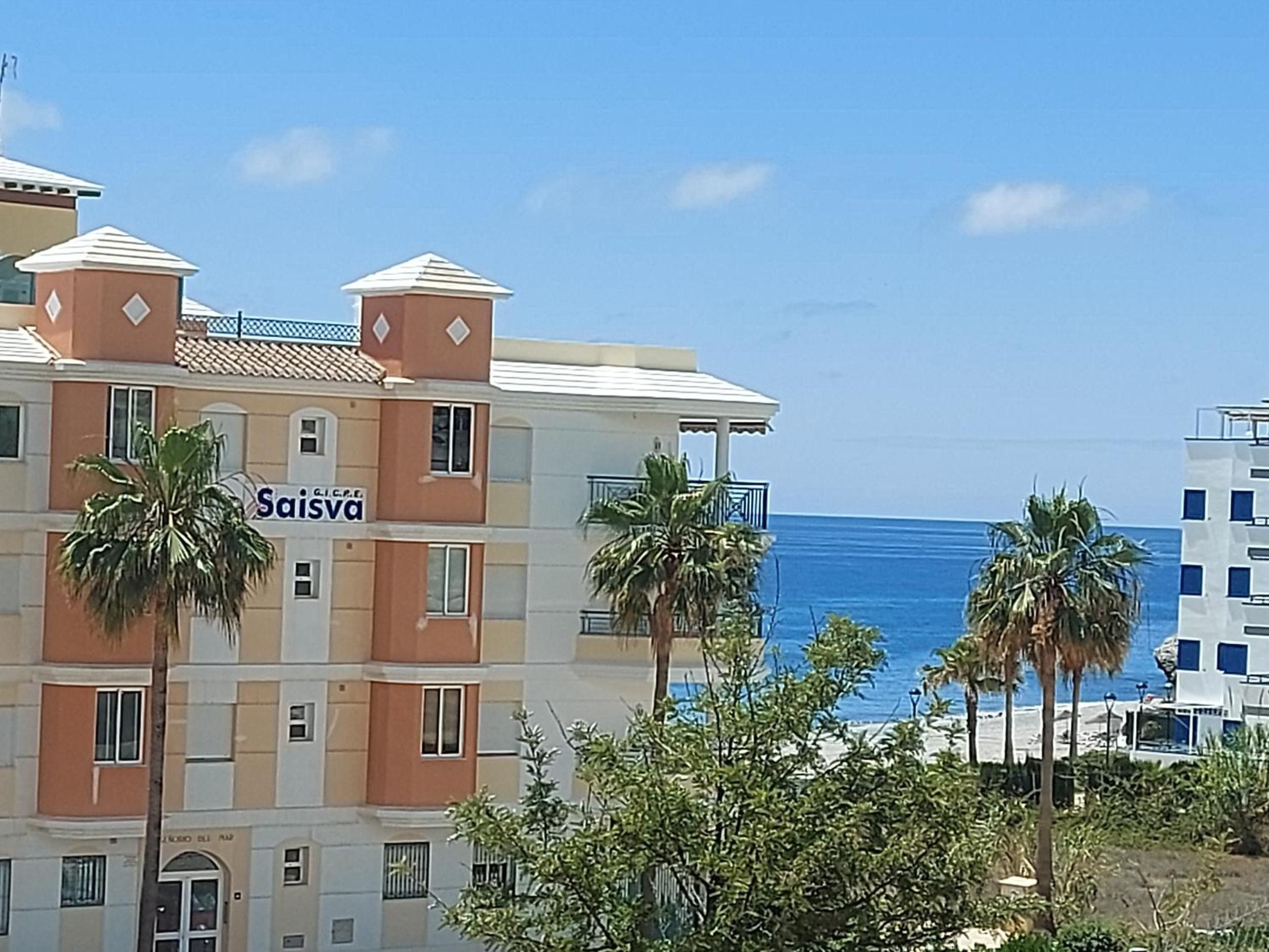 Een meerhoog hotel met een bord waarop 'Saisva' staat, en uitzicht op de oceaan.