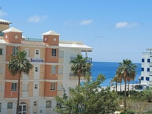 Een meerhoog hotel met een bord waarop 'Saisva' staat, en uitzicht op de oceaan.