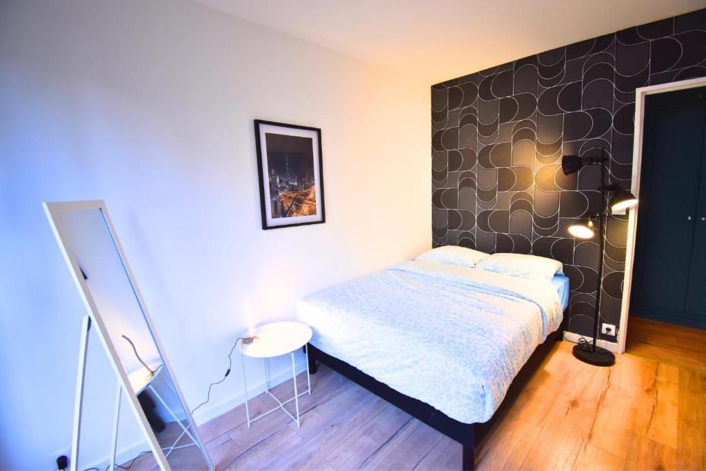 Un dormitorio con cama, un cuadro en la pared, una lámpara de pie y un espejo.