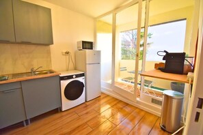 A compact kitchen with a washing machine, a microwave, and a sink. - Aur'Coloré Paris (Aubervilliers)