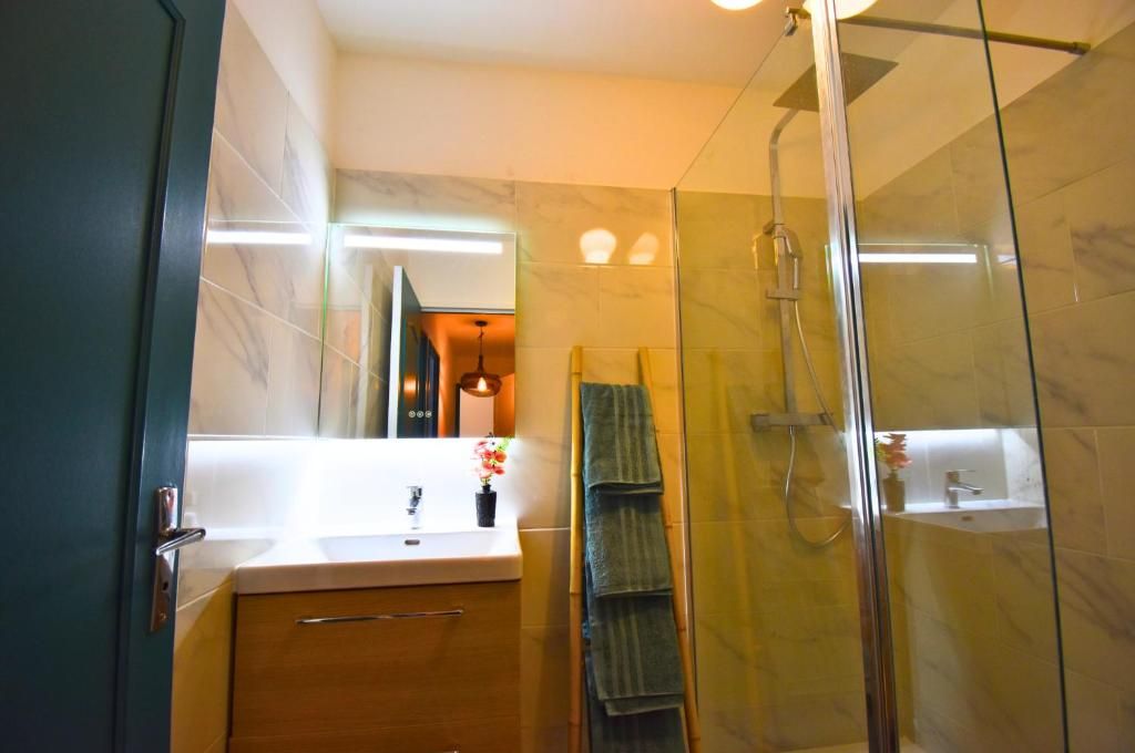 Un baño moderno con cabina de ducha de vidrio, un mueble de madera y un espejo con iluminación integrada.