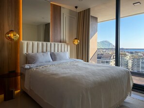 Un dormitorio moderno con una cama grande, dos lámparas de noche y vistas a la ciudad.