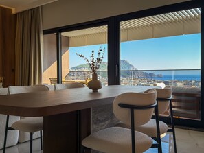 Un comedor moderno con una mesa grande, sillas y vistas a un paisaje urbano costero.
