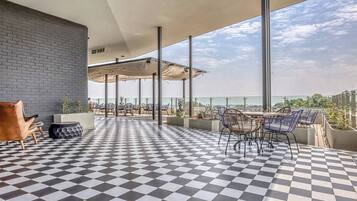 Una terraza en la azotea con piso a cuadros, mobiliario exterior y vistas de la ciudad.