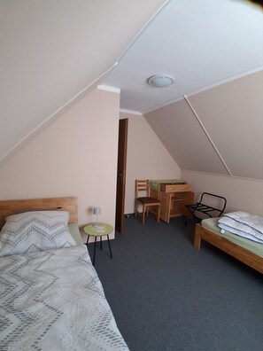 Ein kleines, dreieckiges Schlafzimmer im Dachgeschoss mit einem Bett, einem Schreibtisch und einem Stuhl.