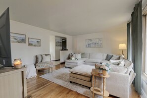 A living room with a sofa set, a coffee table, a side table with a lamp, and a rug. There are framed pictures on the walls. - Walk to Lambeau! Cozy Green Bay Cottage! (Green Bay)