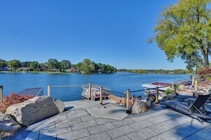 Un muelle frente al lago con barcos, un patio de piedra y vistas a casas al otro lado del agua.