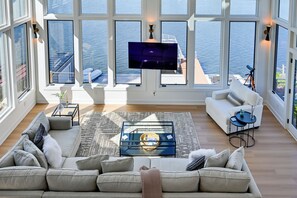 Amplia sala de estar con un ventanal que da al mar, un sofá cómodo, una mesa de centro y un televisor de pantalla plana montado en la pared.