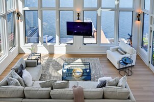 Amplia sala de estar con un ventanal que da al mar, un sofá cómodo, una mesa de centro y un televisor de pantalla plana montado en la pared.