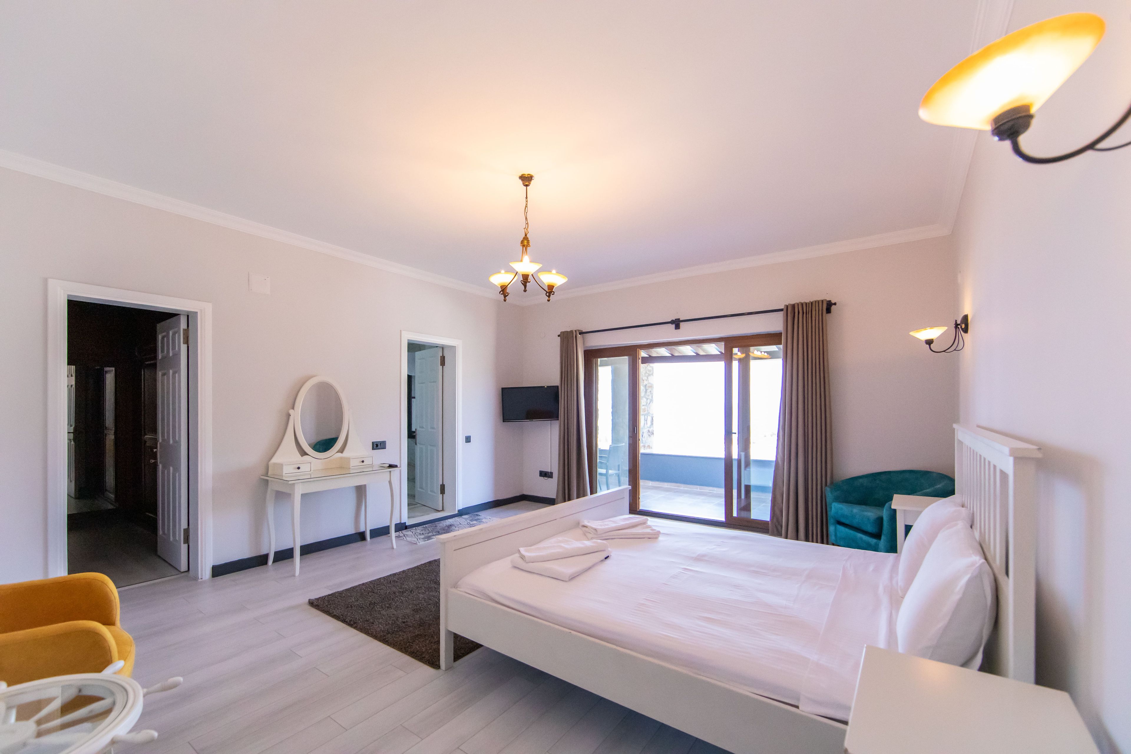 A hotel room with a bed, a desk, a chair, a mirror, and a television.