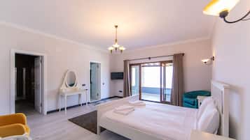 A hotel room with a bed, a desk, a chair, a mirror, and a television.