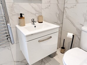 Une salle de bain moderne avec un lavabo blanc, des toilettes et un porte-serviettes.