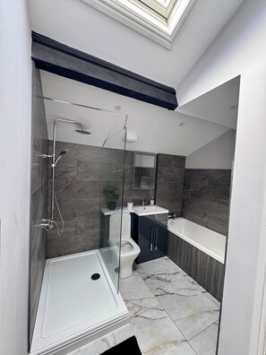 Un baño moderno con ducha acristalada, inodoro y bañera.