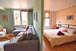 Ein Zimmer mit einer Couchgarnitur, einem Bett, einem Sessel und einer Heizung.
