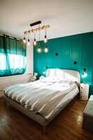 Un dormitorio con cama, lámparas de noche y una pared de acento color turquesa.