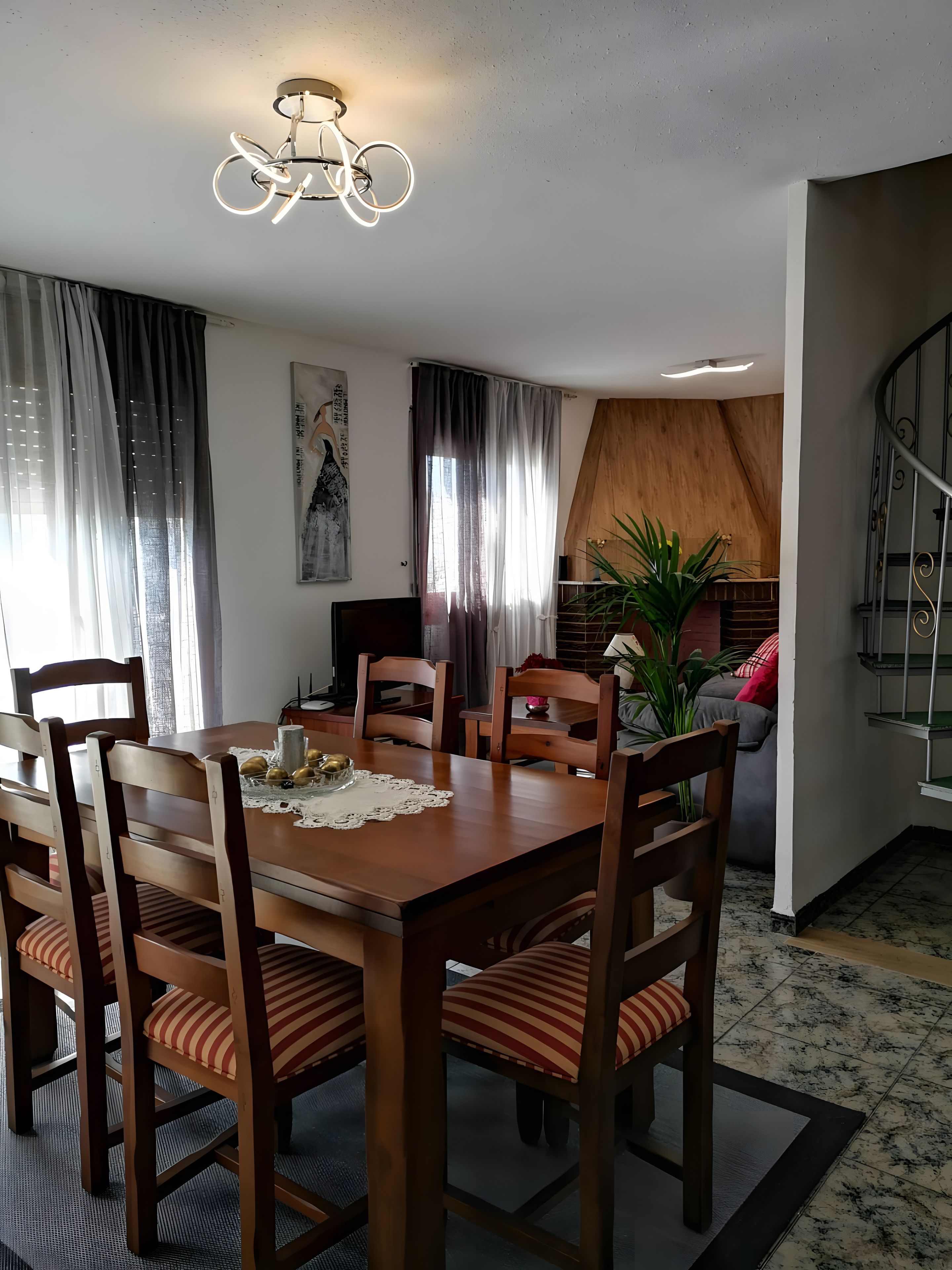 Un comedor con una mesa de madera, sillas y una araña.