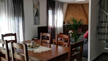Un comedor con una mesa de madera, sillas y una araña.