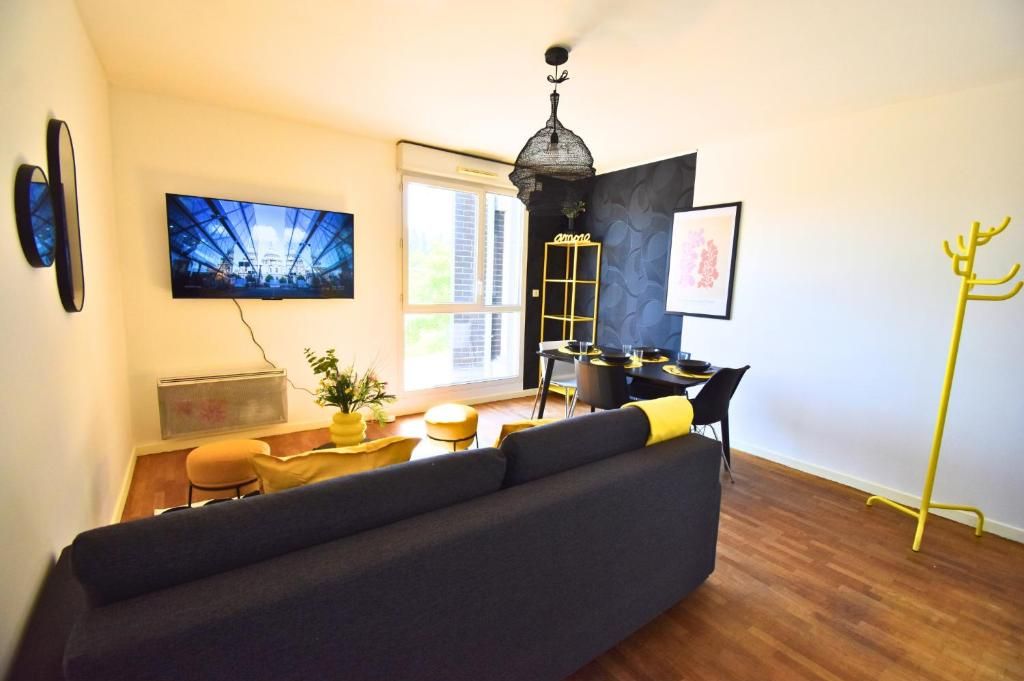 Una sala de estar moderna con un sofá, un televisor, una mesa de comedor y un perchero amarillo.