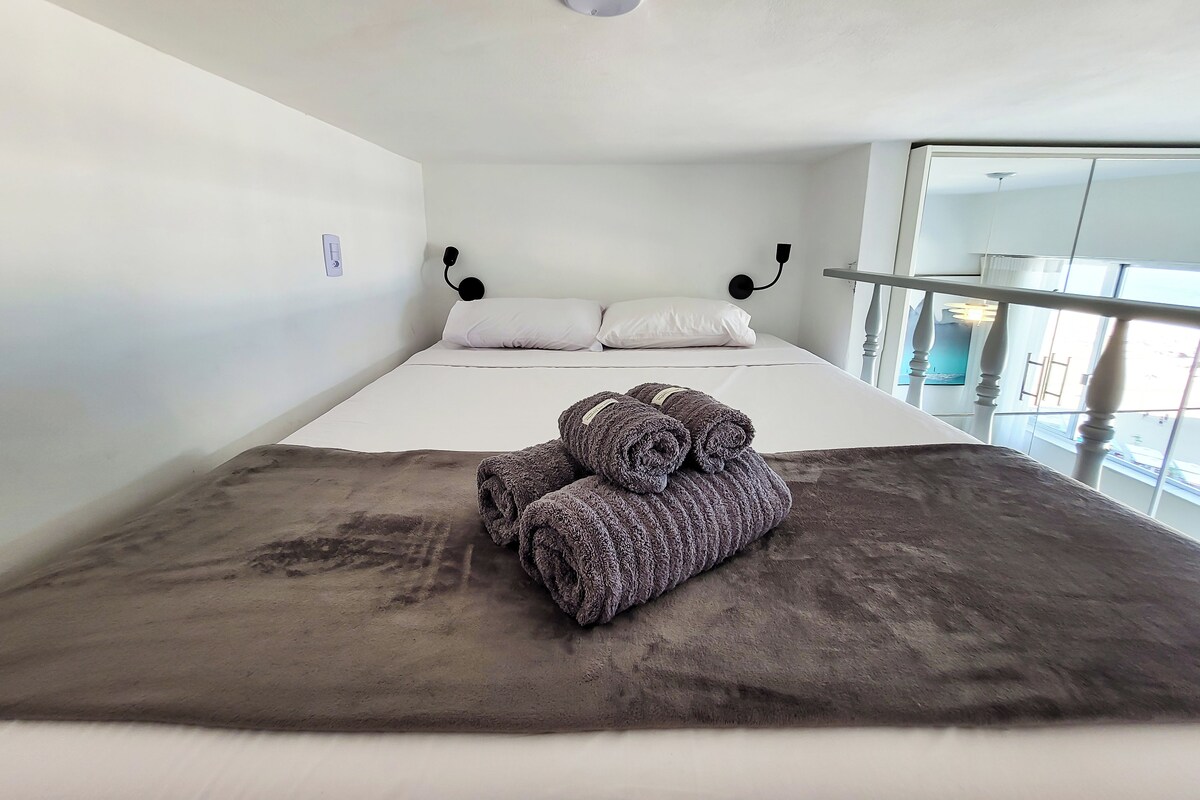 Hotellihuone, jossa on sänky, suuri ikkuna ja näkymä ulos.