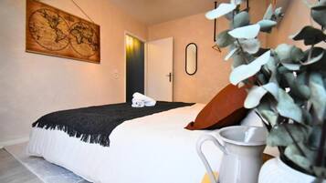 Ein Schlafzimmer mit einem Bett, einer an der Wand hängenden Karte, einer Tür und einer Pflanze.