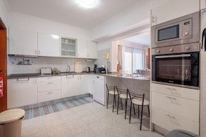 Eine moderne Küche mit weißen Schränken, einem Backofen und einer Mikrowelle.