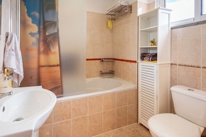 Ein Badezimmer mit Badewanne, Waschbecken, Toilette und einem Handtuchregal.