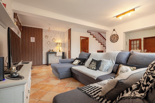 Ein Wohnzimmer mit Ecksofa, einem kleinen Tisch und einem Fernseher.