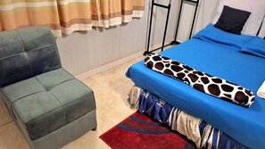 A room with a bed, a chair, a striped curtain, and a red rug. - Kalebalika Cottages  (Kasama)