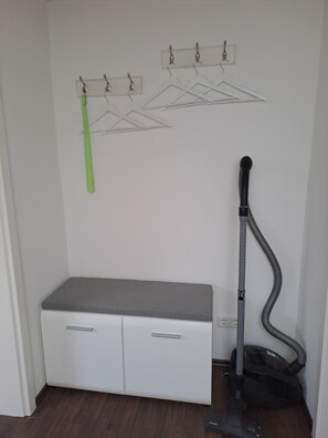 Ein Zimmer mit einem weißen Schrank, einem Staubsauger und einem Wäschest änder.