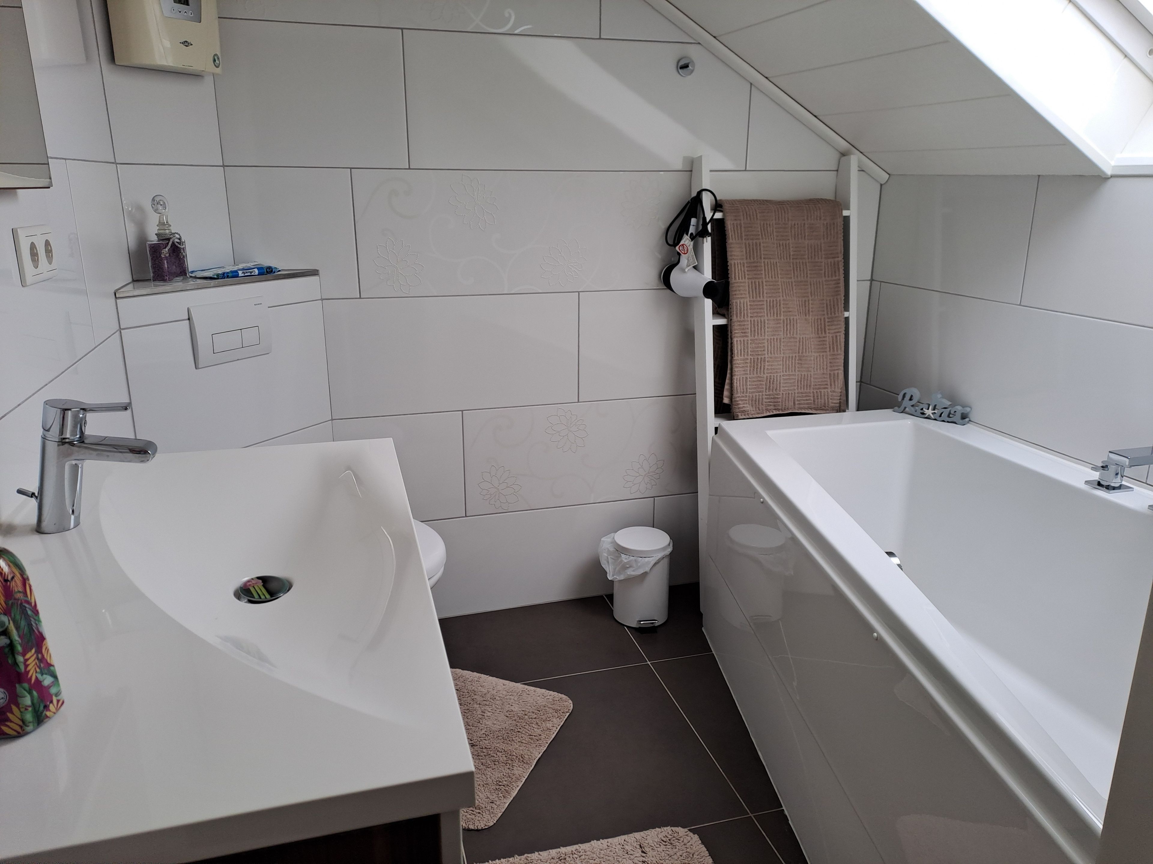 Ein modernes Badezimmer mit Waschbecken, Badewanne und Toilette in Weiß.