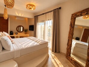 Une chambre d’hôtel avec un lit, un grand miroir, une télévision et une fenêtre avec des rideaux.